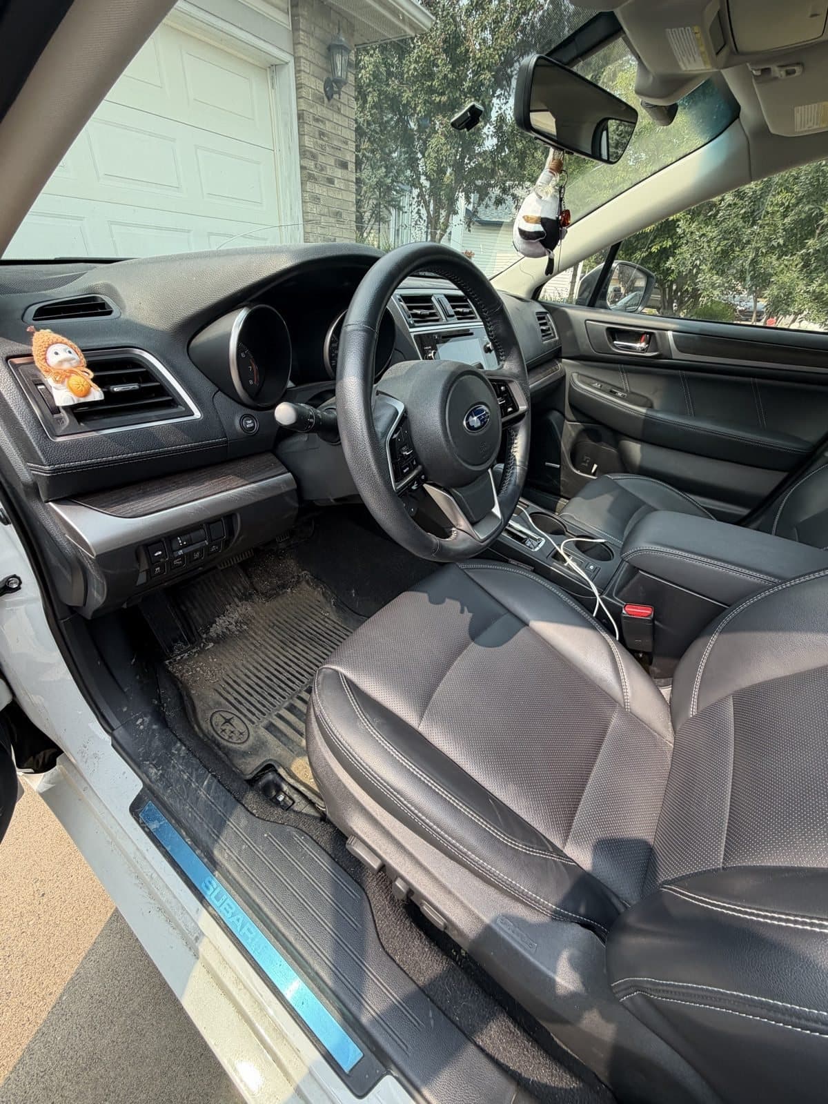 Subaru Outback driver side before detailing, with a dirt-covered floor mat and grimy sill